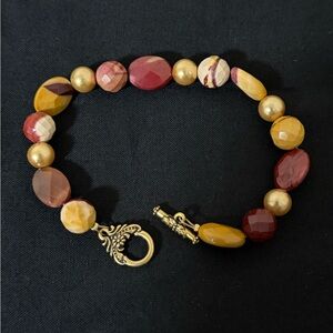 Mookaite jasper and gold-tone bead bracelet with a decorative toggle clasp.